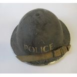 A WW2 metal helmet, painted black with POLICE in white to one end