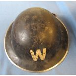 A WW2 metal helmet, painted black with a white "W", stamped 1939 to the rim