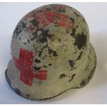 A WW2 German style helmet, painted white with red cross to front, back and top, and SS badge to