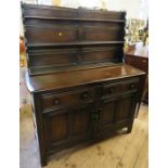 An Ercol dark oak dresser base, two cupboards and two drawers below, width 51ins together with an