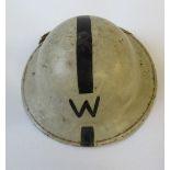 A WW2 metal helmet, painted white with a single black stripe and "W"