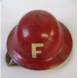 A WW2 metal helmet, painted in red with a white "F" to each end, impressed 1943 to the rim