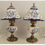 A pair of modern porcelain and gilt metal table lamps, with pierced porcelain shades, decorated in