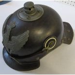 A pickelhaube style helmet with neck protector, having stunted metal spike, and decorated with a