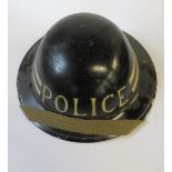A WW2 metal helmet, painted black with two white bands and POLICE in white to one end, impressed