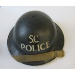 A WW2 metal helmet, painted black with SC POLICE in white to one end