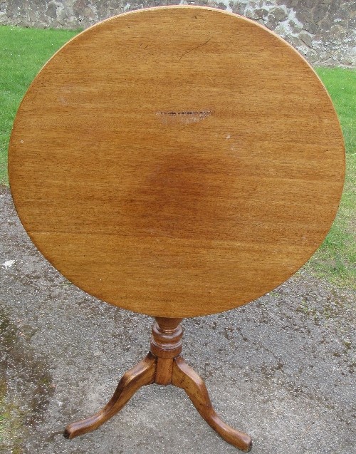 An antique mahogany circular tilt top table, raised on a turned column to a triform base, diameter