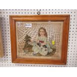 A 19th century framed tapestry picture of a seated girl with a dog on her lap, in a birdseye maple
