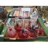 A collection of cranberry and other glass, including decanters