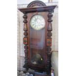 A walnut cased wall clock, with Roman numerals, the case with glazed door and turned half columns,