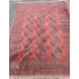 A red ground Eastern design rug, with a central row of medallions, 110ins x 80ins
