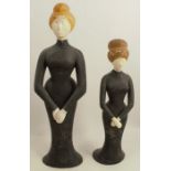 Two 20th century painted wooden models, of woman wearing black dresses, heights 17.5ins and 14ins