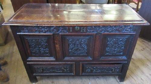 An antique oak mule chest, with rising lid, the front carved with flowers and leaves, fitted with