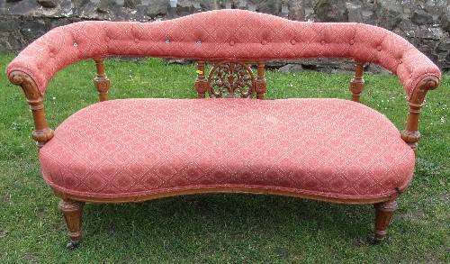 A Victorian show wood settee, with upholstered shaped top rail, having carved and turned supports to