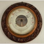 A wall barometer, of circular form, having a carved frame decorated with acorns and oak leaves,