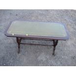 A reproduction coffee table, having green leather inset top, raised on reeded legs terminating in