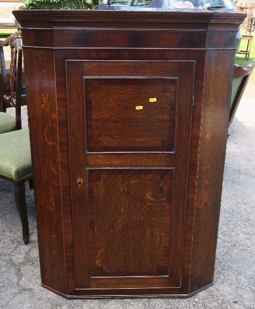 An Antique oak corner cupboard, with mahogany banding to the door, fitted with three shelves,