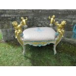 A continental stool, having four capitals formed as stylised putti, united by upholstered  seat,