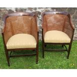 A pair of bergere armchairs, with curved backs and raised on square tapering front supports