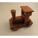 A toy wooden steam train, raised on four turned wooden wheels and fitted with a clockwork music box