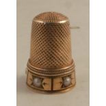 An unmarked gold thimble, set with half pearls, one missing