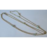 A long chain, in unmarked gold, punctuated at intervals with a total of twelve opal beads, of
