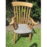 A lathe back Windsor armchair, with upholstered seat and raised on turned legs, united by an H