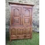 An antique design cupboard, having two fielded panel doors opening to reveal hanging space, over a
