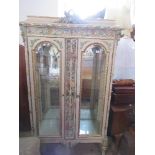A continental style painted and glazed display cabinet, having painted and carved decoration all