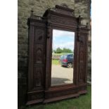 A continental oak mirror door wardrobe, having carved freeze over mirror door, flanked by two carved