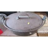 A large oval covered pan, with swing handle, maximum diameter 22ins