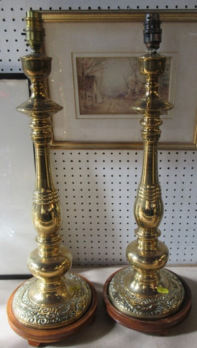 A pair of brass lamp bases, with multi knop stems, and the bases decorated with dragons, on wooden