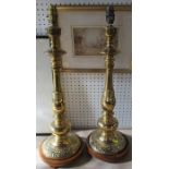 A pair of brass lamp bases, with multi knop stems, and the bases decorated with dragons, on wooden