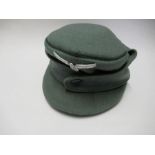 A German Third Reich style M43 single button field cap, in green wool, bearing white metal RMBO to