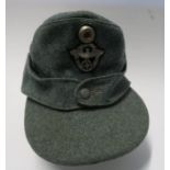 A WW2 style German police M43 field cap, in green wool, with cloth badge to front and single button,