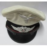 A Third Reich Kriegsmarine style visor cap, in white canvas style cloth, red piping to the black hat
