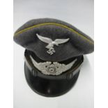 A Third Reich style visor cap, in dark grey wool, with gold coloured piping and black hat band,