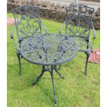 A pierced metal circular garden table and two chairs