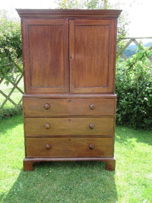 A 19th century mahogany press cupboard, having two panel doors opening to reveal three slide out