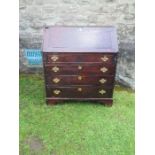 A late Georgian oak bureau, the fall flap opening to reveal cupboards, secret drawers, pigeonholes