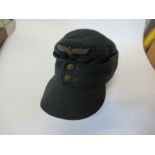 A German Third Reich style M43 field cap, in dark green wool, with metal stitched RMBO logo above