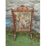 A walnut fire screen, the embroidered panel flanked by barley twist columns, below a carved