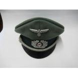 A Third Reich style visor cap, in green felt fabric with dark green piping and hat band, silver