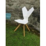 A white plastic chair with geometric shaped back and seat raised on metal chairs