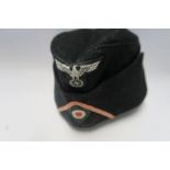 A Third Reich style M38 side hat, in black wool, having appliqued white RMBO logo to the front above