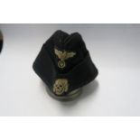 A Third Reich style M38 side hat, in black wool, with appliqued white RMBO motif to the front, above
