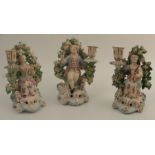 Three 18th century Derby porcelain figural candlesticks, formed as seated figure by flowering trees,