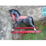 A painted rocking horse, on the remains of a red base