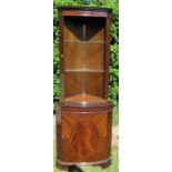 A mahogany veneered floor standing corner cabinet