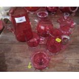 Four cranberry glass jugs, together with two other cranberry glass items